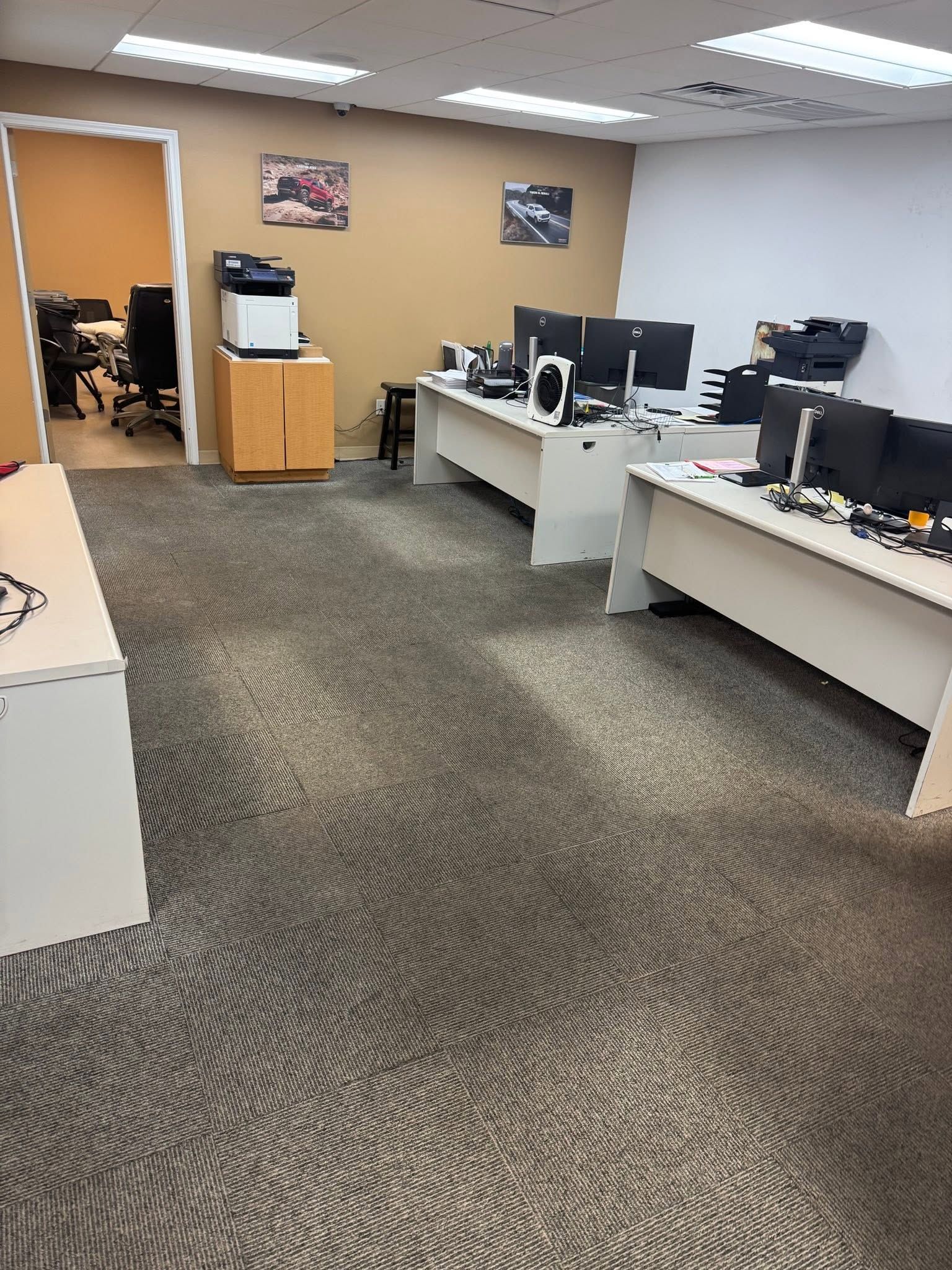 Office workspace with desks, computers, and a water cooler on a patterned carpet.