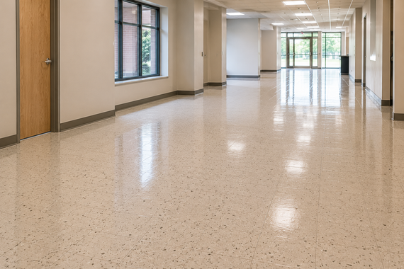 Empty school hallway with polished speckled floor, beige walls, and windows letting in daylight