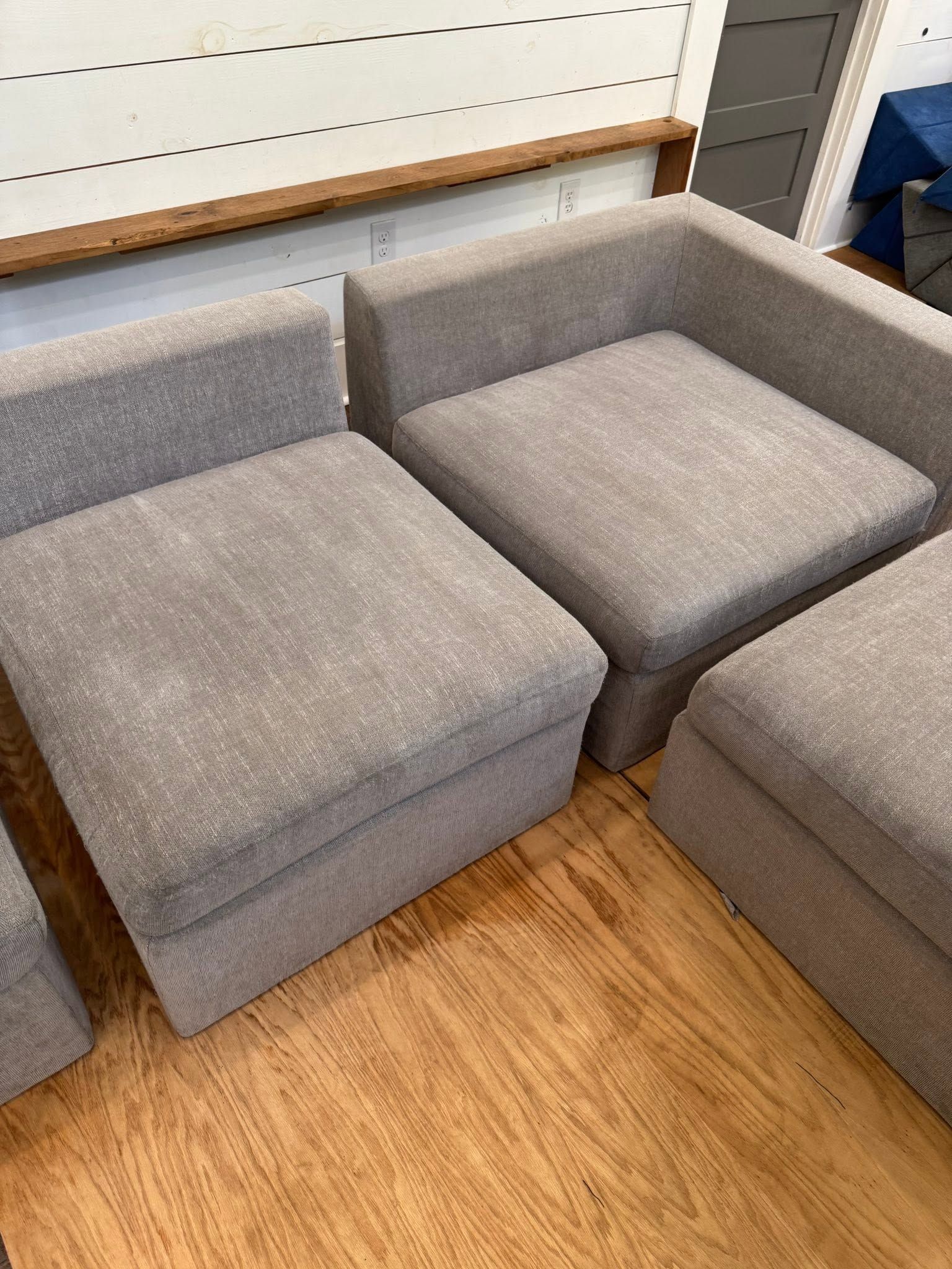 Gray modular lounge chairs arranged in a corner on a wood floor in a room