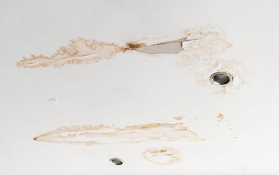 White wall with rust stains and two holes, one large dark hole on the right and a small one near the bottom.