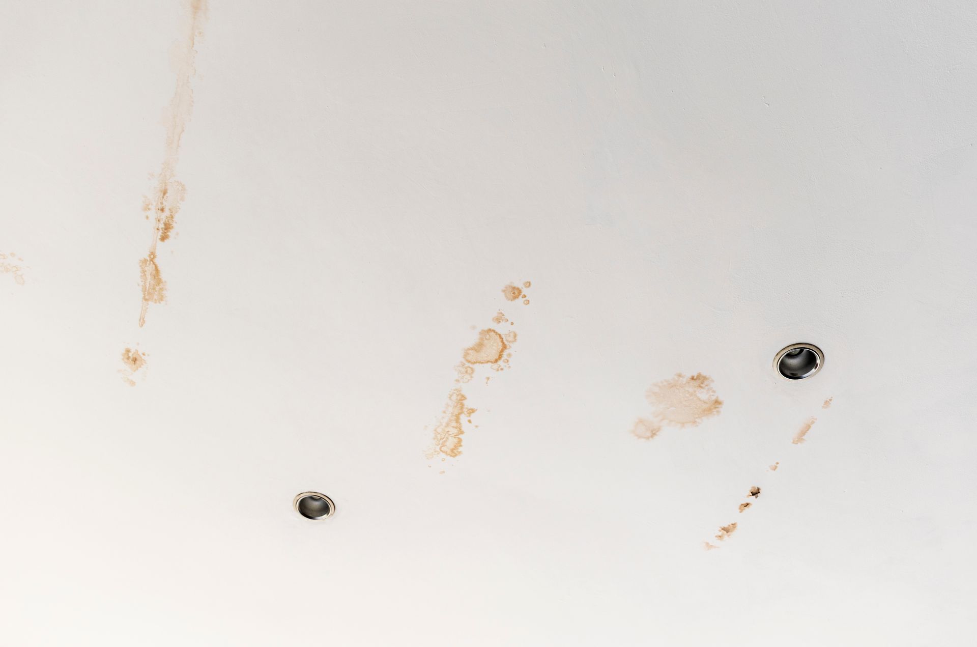 White wall or ceiling with two screw holes and several brown scuff marks.