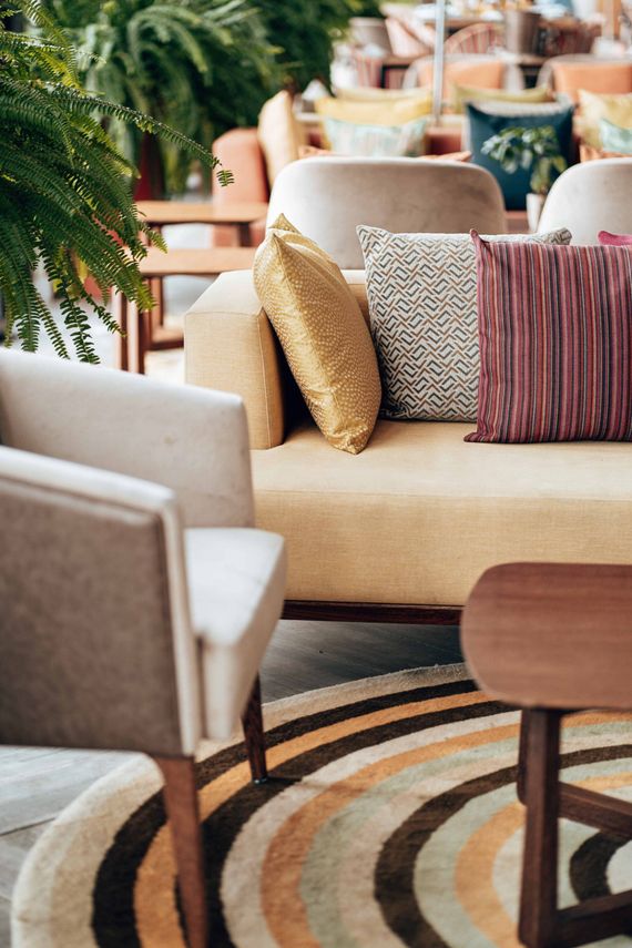 Cozy lounge with beige sofas, patterned pillows, and a round table on a striped rug