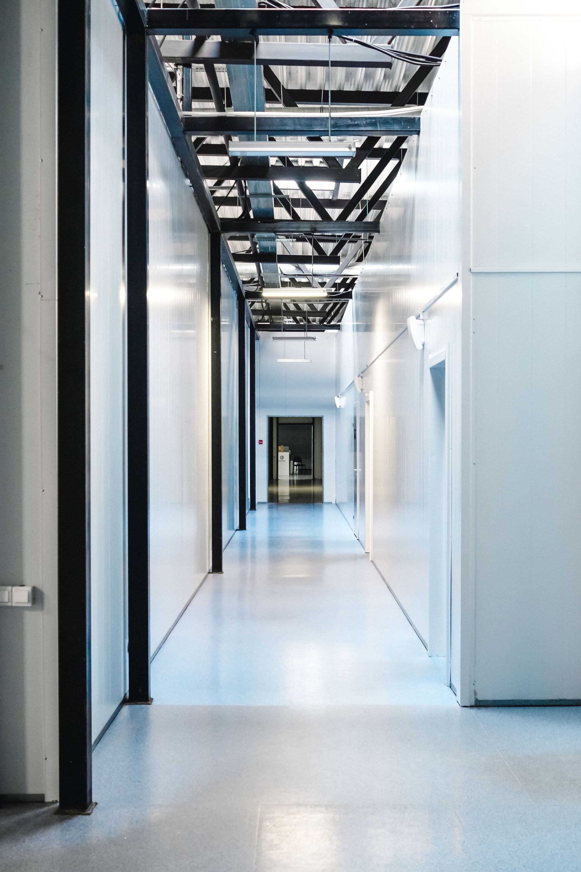 Empty white hallway with exposed ceiling beams and doors along the sides