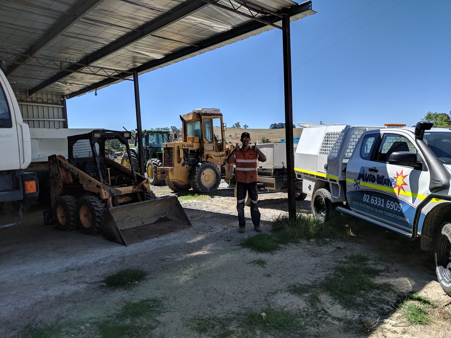 Man Standing in Front of Construction Vehicles Under a Shaded Structure — Auto Watt in Kelso, NSW