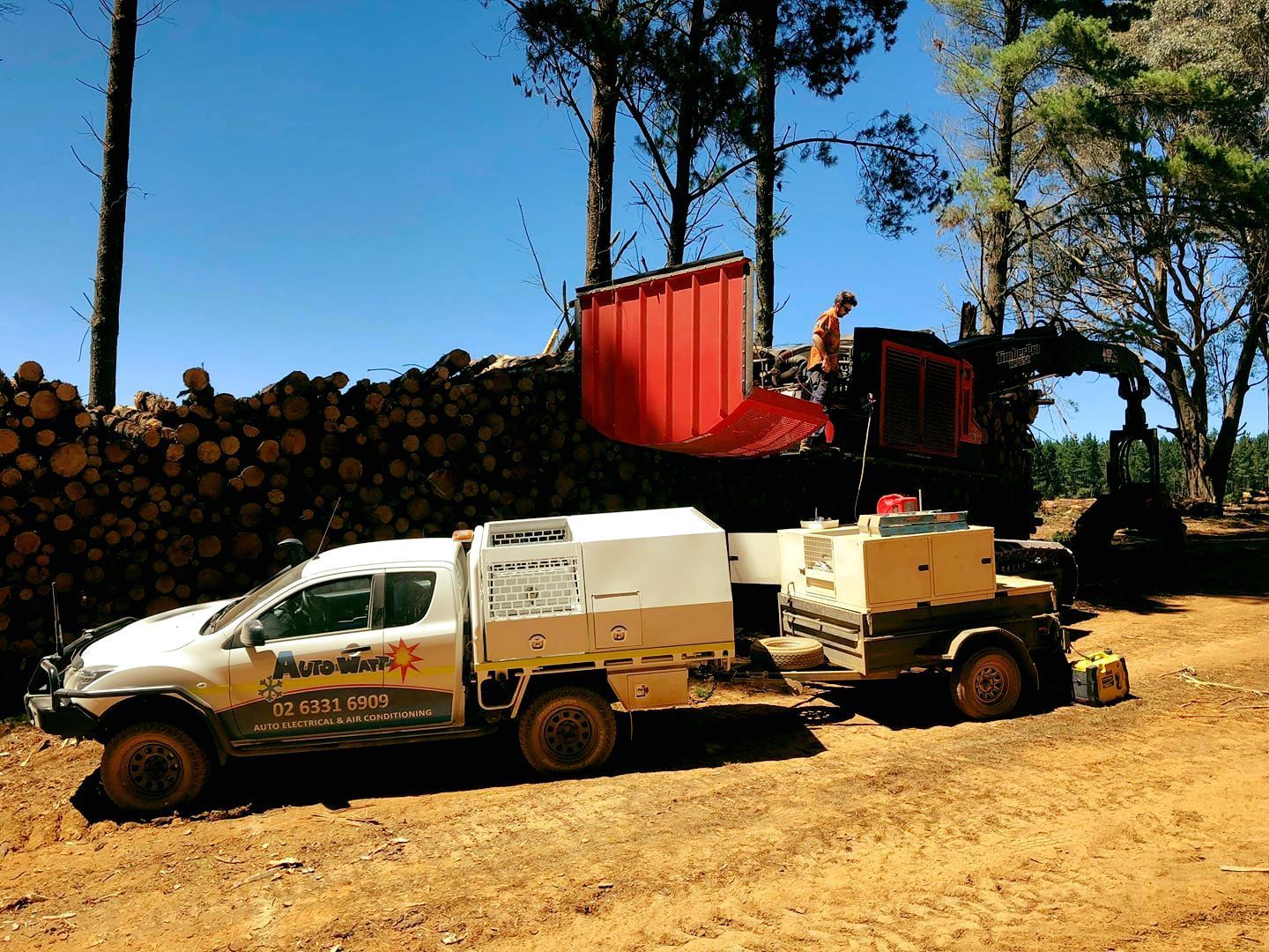 A Wood Chipper Processes Logs Next to a Truck and Trailer in a Forest on a Sunny Day — Auto Watt in Kelso, NSW