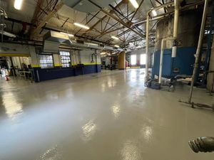 Empty industrial warehouse with blue machinery, polished concrete floor, and overhead skylights