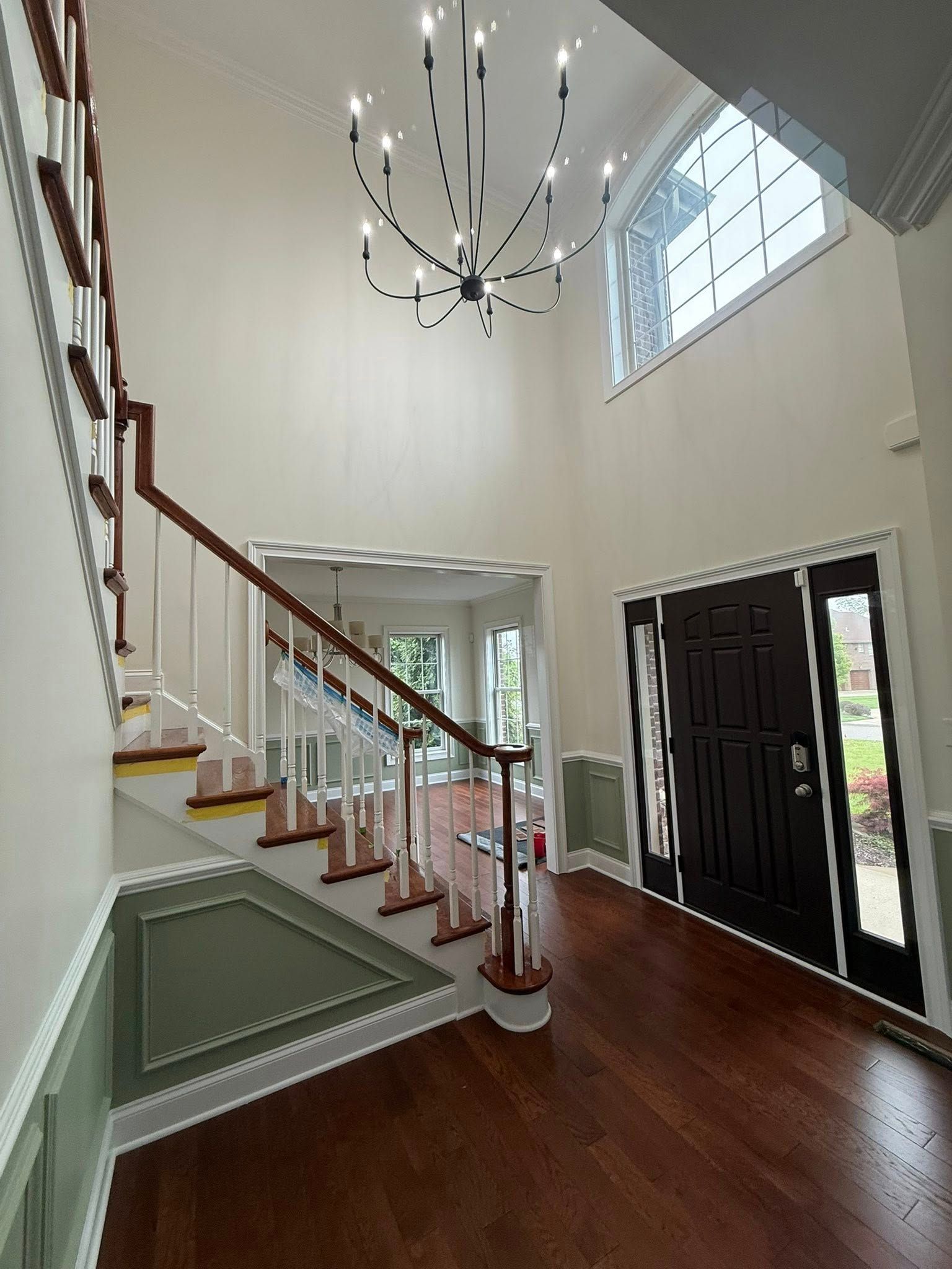 Bright foyer with curved staircase, chandelier, hardwood floors, and double front doors with sidelights