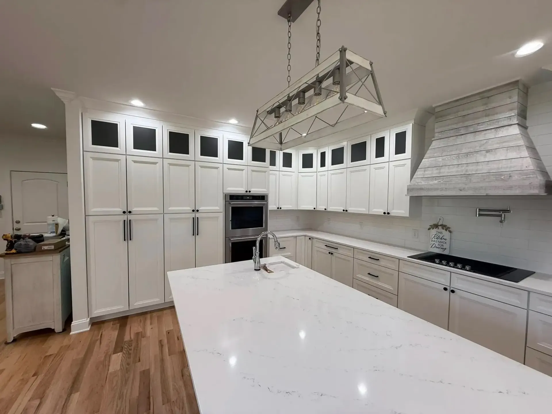 Bright modern kitchen with white cabinets, large island, stainless appliances, and wood floors