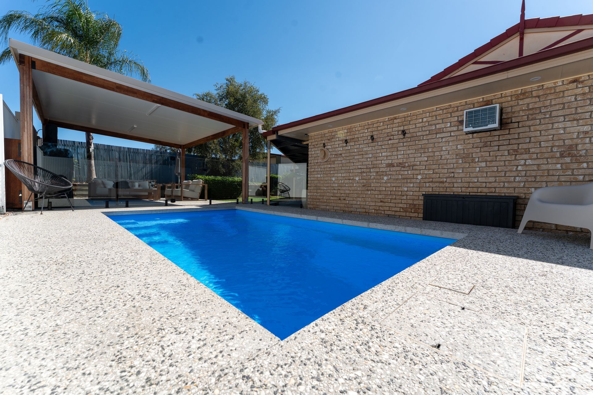 Metal pool ladder leading into clear blue indoor pool water, beside white tiled edge