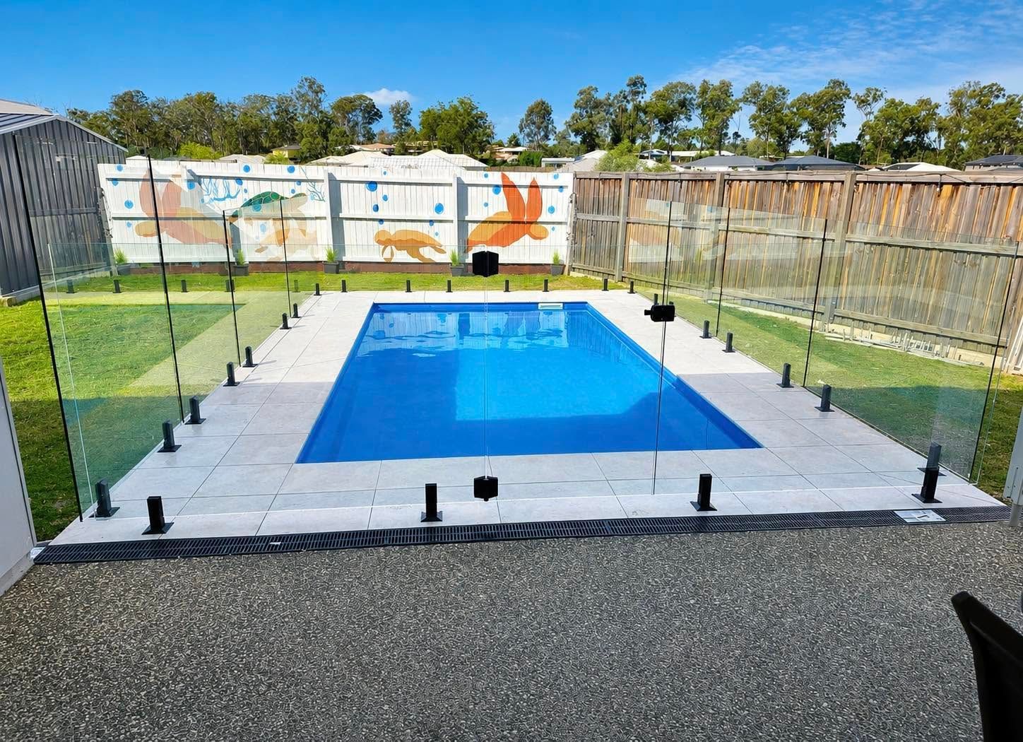 Outdoor lap pool with swimmers, blue lanes, and palm trees on a sunny day