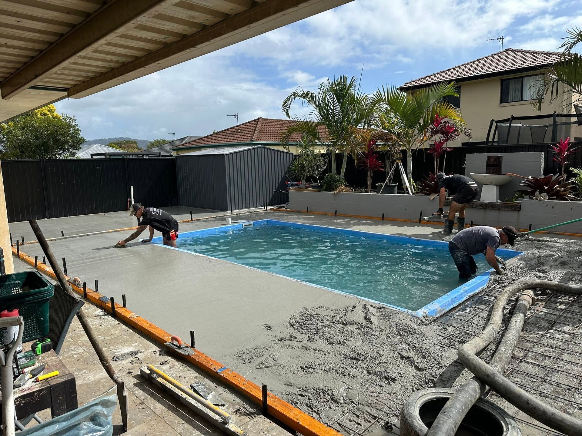 Blue rectangular swimming pool with tiled water and a light stone deck beside it.