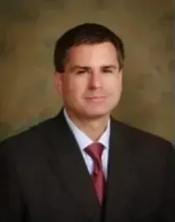 A man in a suit and tie is smiling for the camera