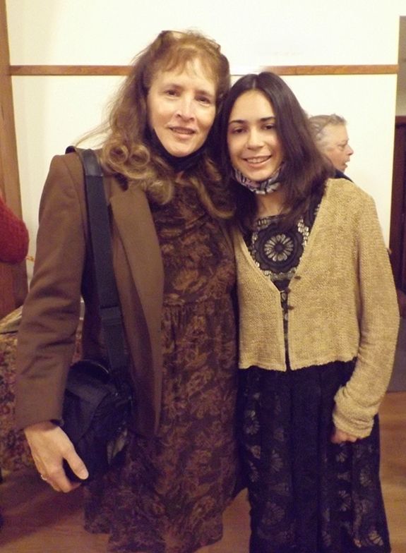 A woman & her daughter stand smiling in their dressy black & tan outfits while attending the 150th Sanctuary 
Commemoration