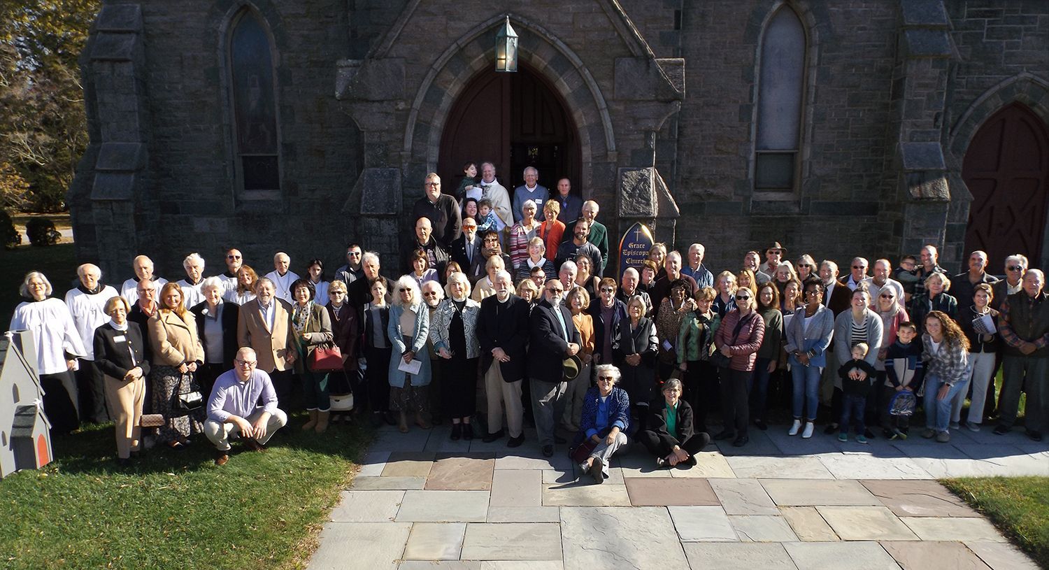 The Congregation poses together outdoors on Grace Church's stone front steps in bright sunlight on All Saints Day 2025