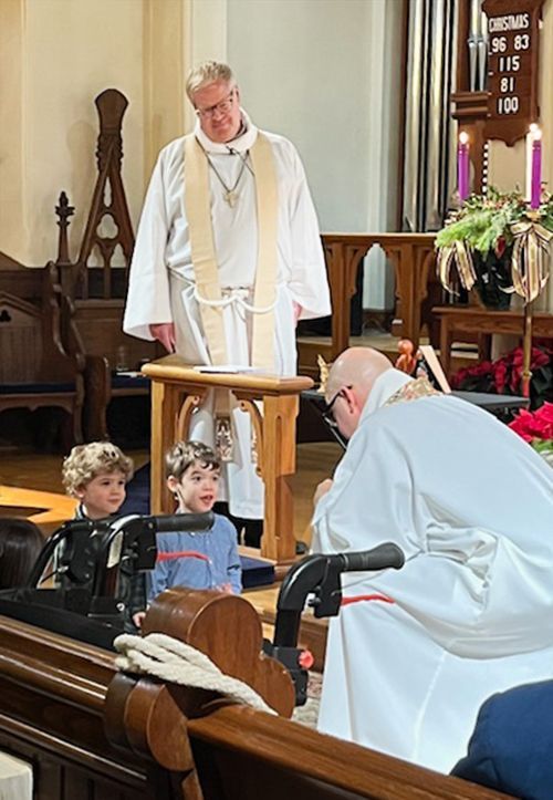 Clergy surrounds children at the beginning of the Christmas Candlelight service