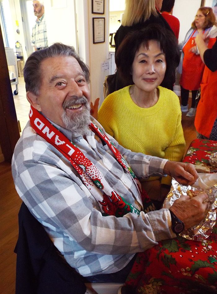 A bearded man & an Asian woman sit smiling at a festive table eating lunch