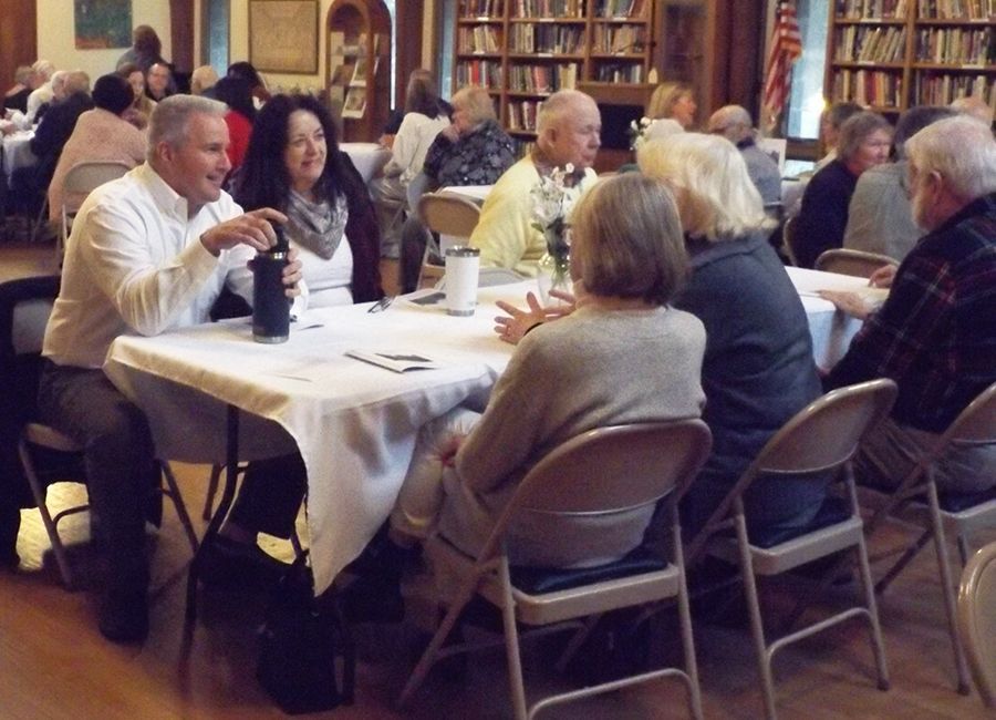 People seated at tables together in the church Parish Hall, socializing before the Maundy Thursday service.
