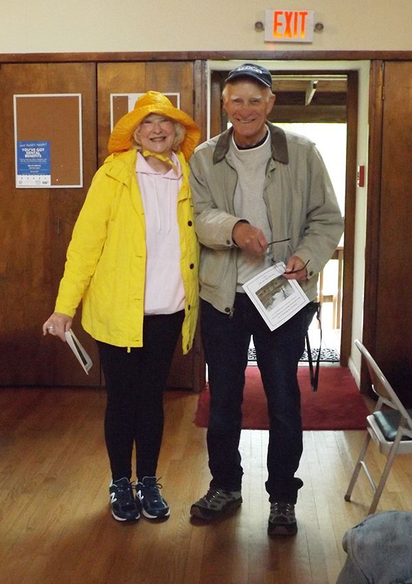 Pastor Ellendale enters the Parish Hall wearing a yellow rain slicker & hat, while walking w/a male parishioner