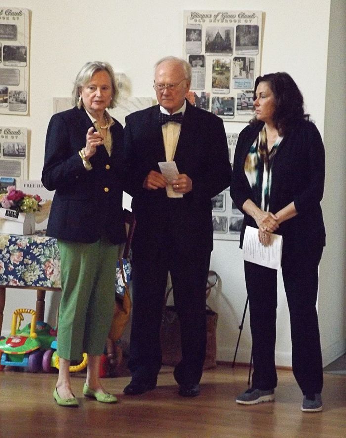 3 people stand together in the Parish Hall beside a poster display
