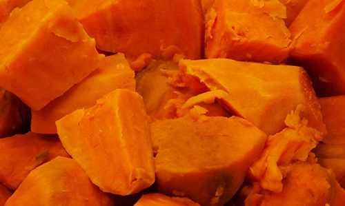 A close-up view of vibrant orange chunks of cooked sweet potatoes piled together.