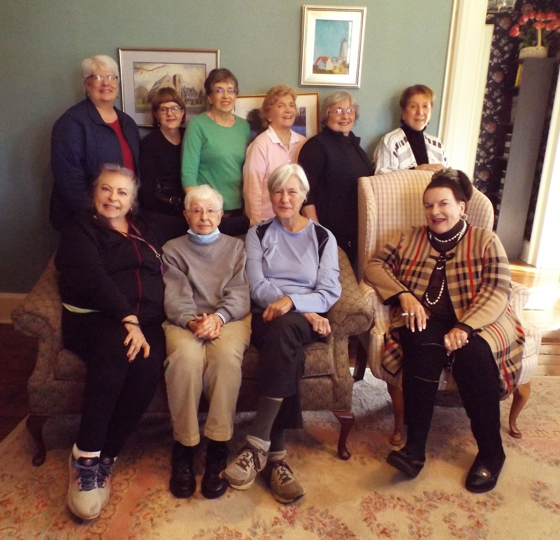 The Women of Grace Bible Study Group members pose in seated & standing rows, w/framed art on the wall behind them