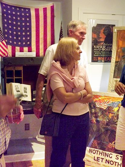 A man & woman stand in front of an American flag & themed posters indoors