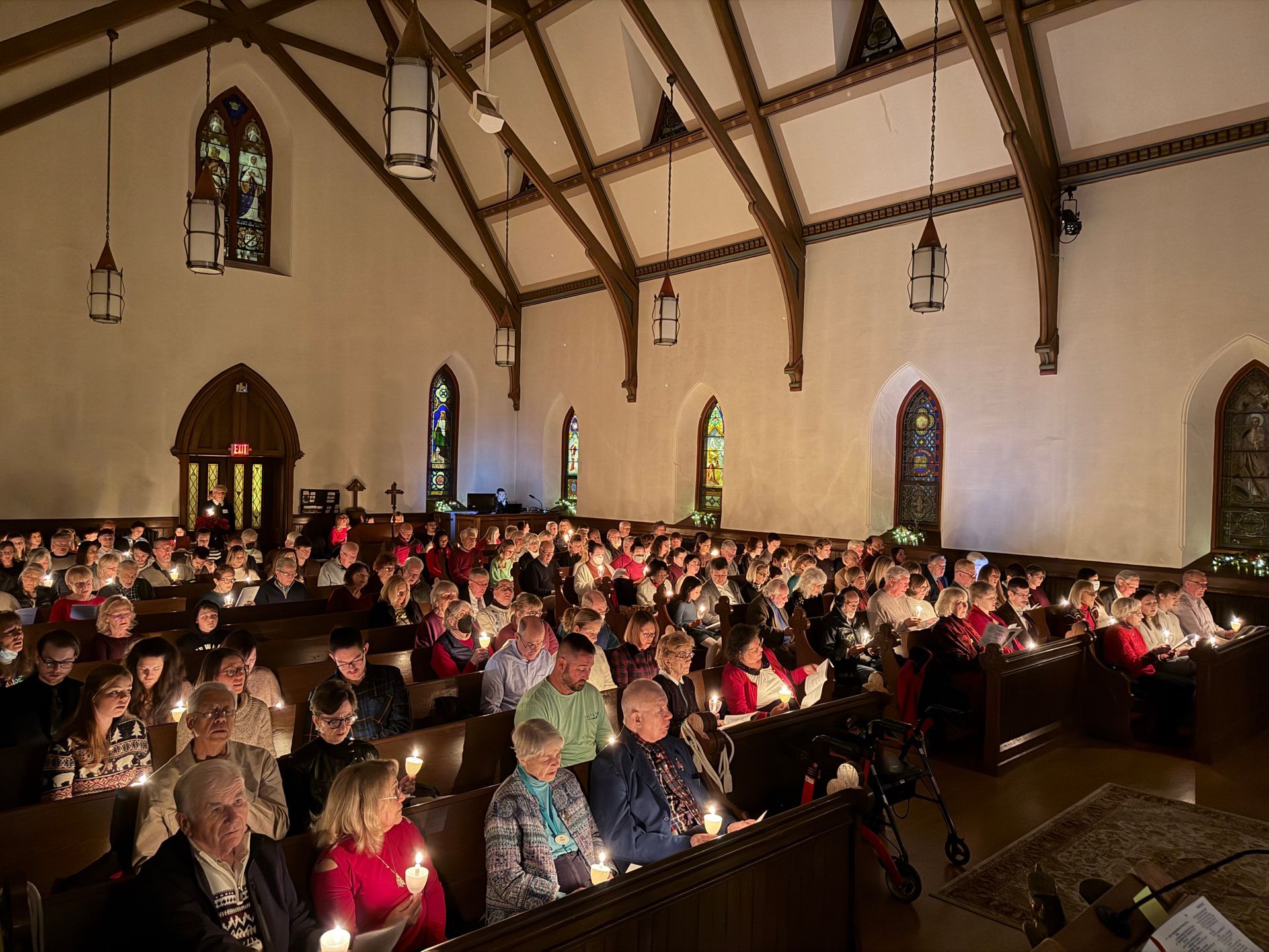 The candlelit congregation sits crowded into the full pews of the church sanctuary during the Christmas Eve vigil