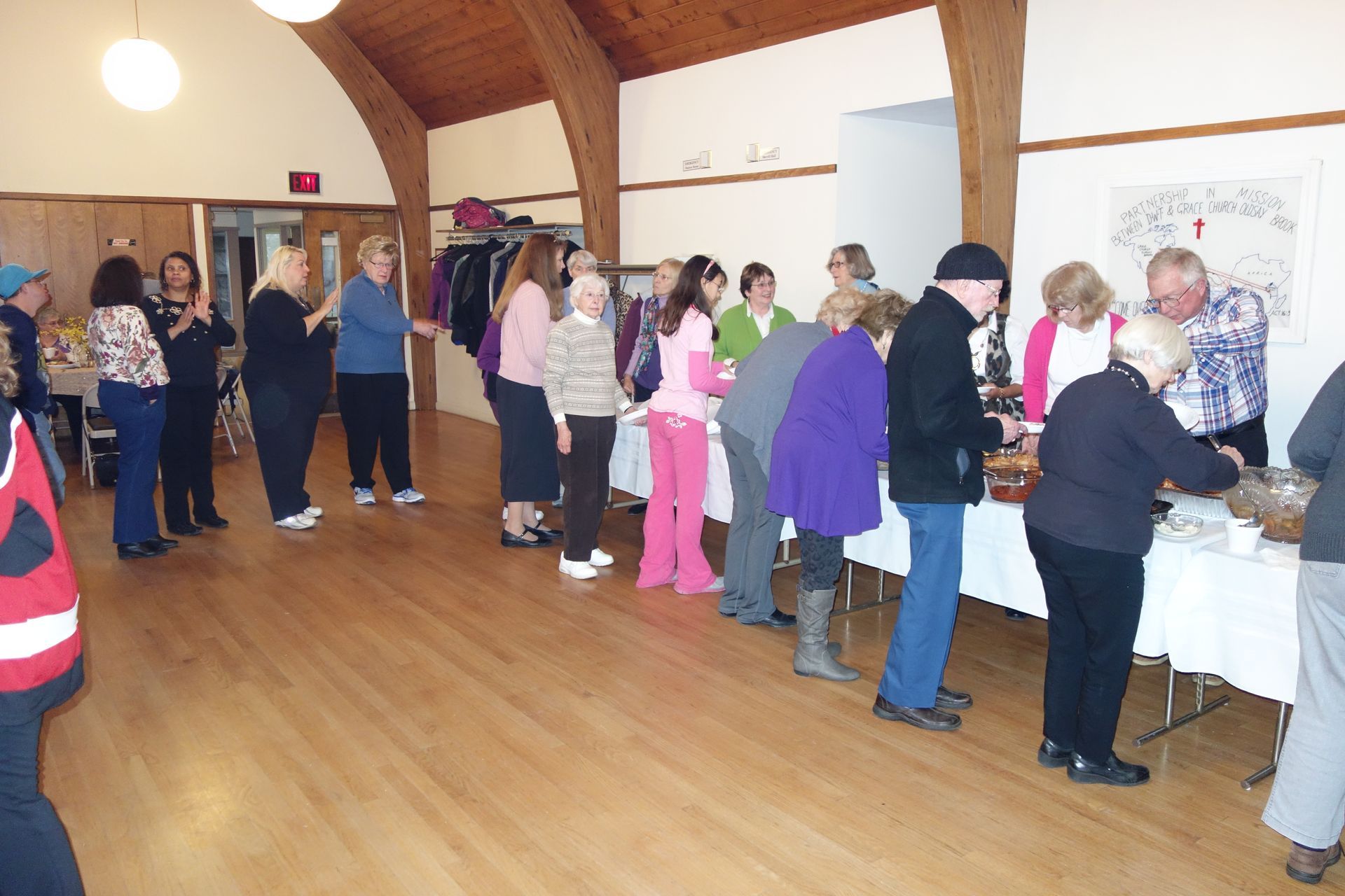 Parishioners line up at a food-serving table in the wood-floored Parish Hall.