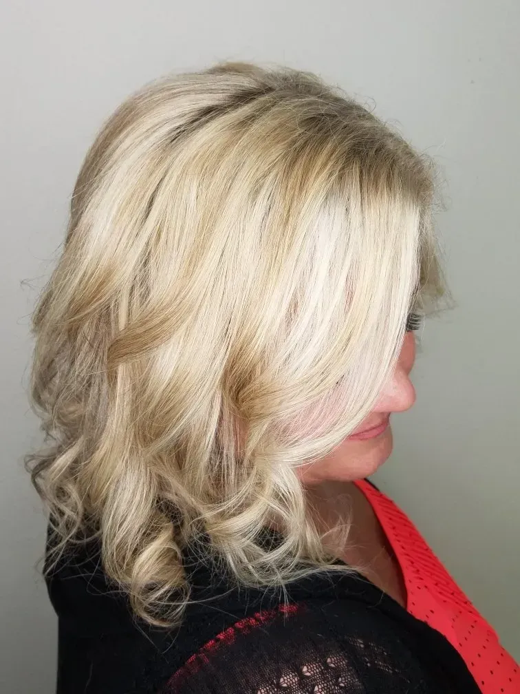 Side view of a woman with shoulder-length blonde hair and a red top against a gray background