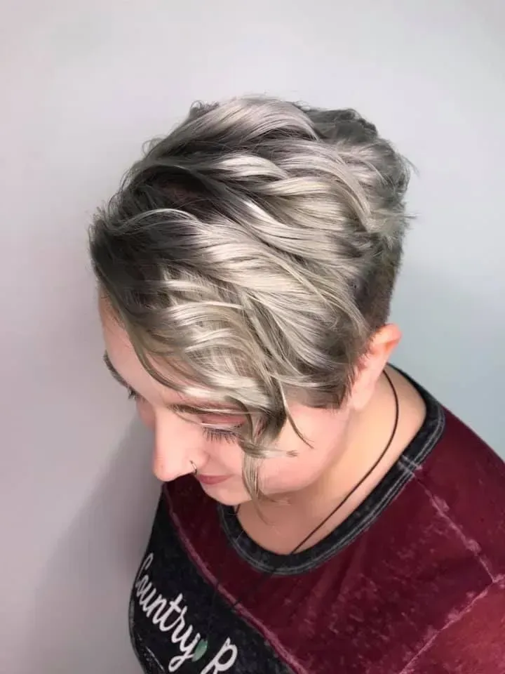 Short silver-blond hairstyle with dark roots, shown from above against a plain background