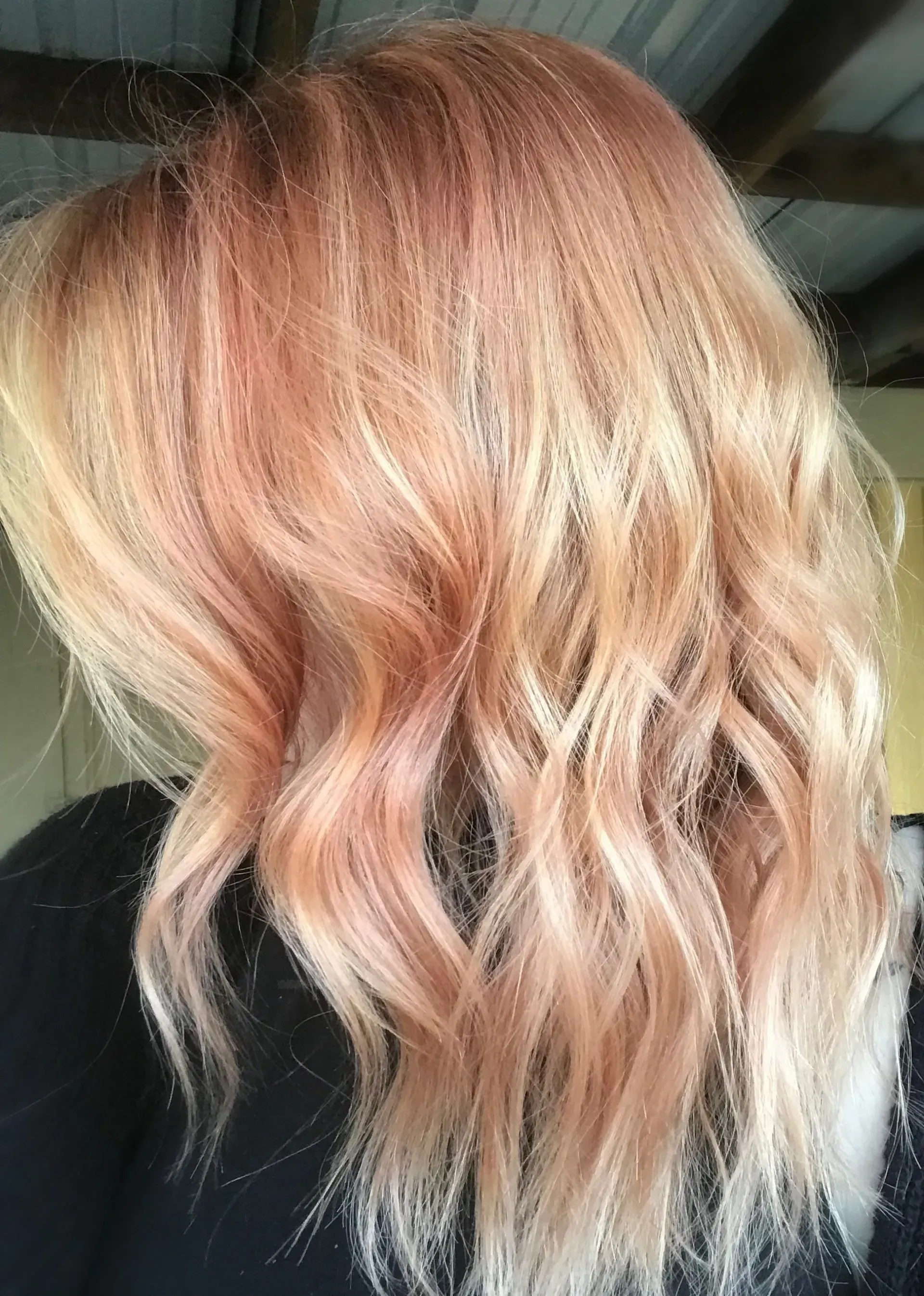 Wavy rose-gold blond hair with soft pink highlights, shown against a dark background