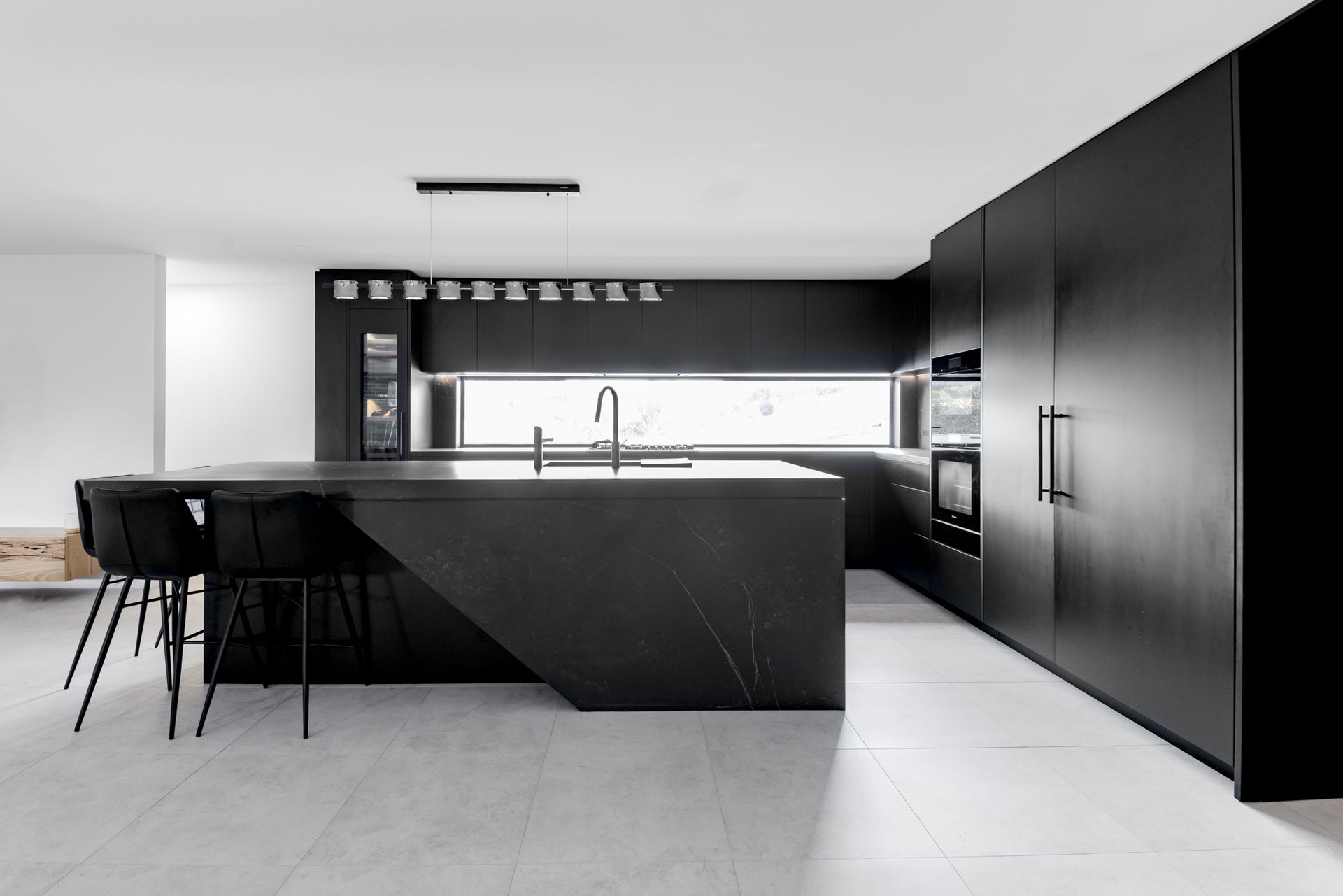 An all-black sleek kitchen featuring matte joinery and black veined stone surfaces.