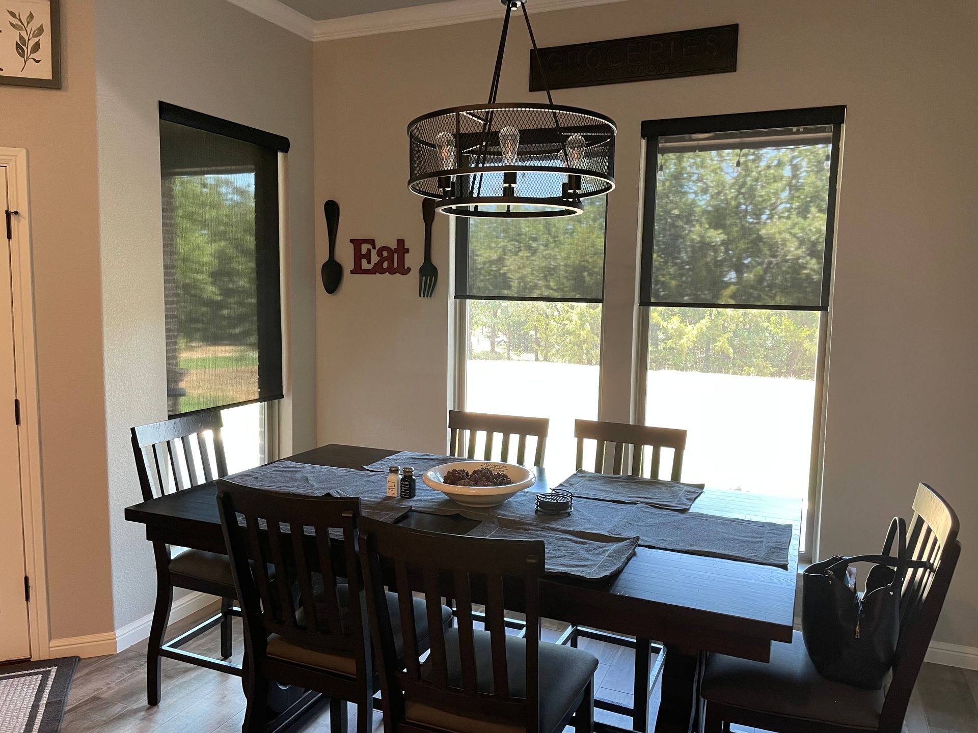 A dining room with a table and chairs and a sign that says eat on the wall.