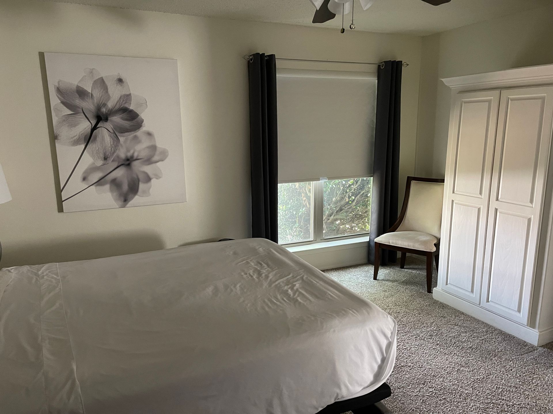 A bedroom with a bed , chair , closet and window.