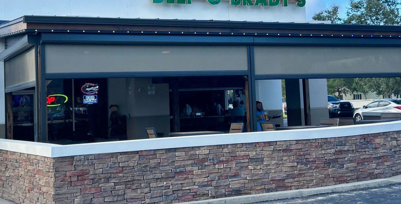 A restaurant with a stone wall and a covered patio.