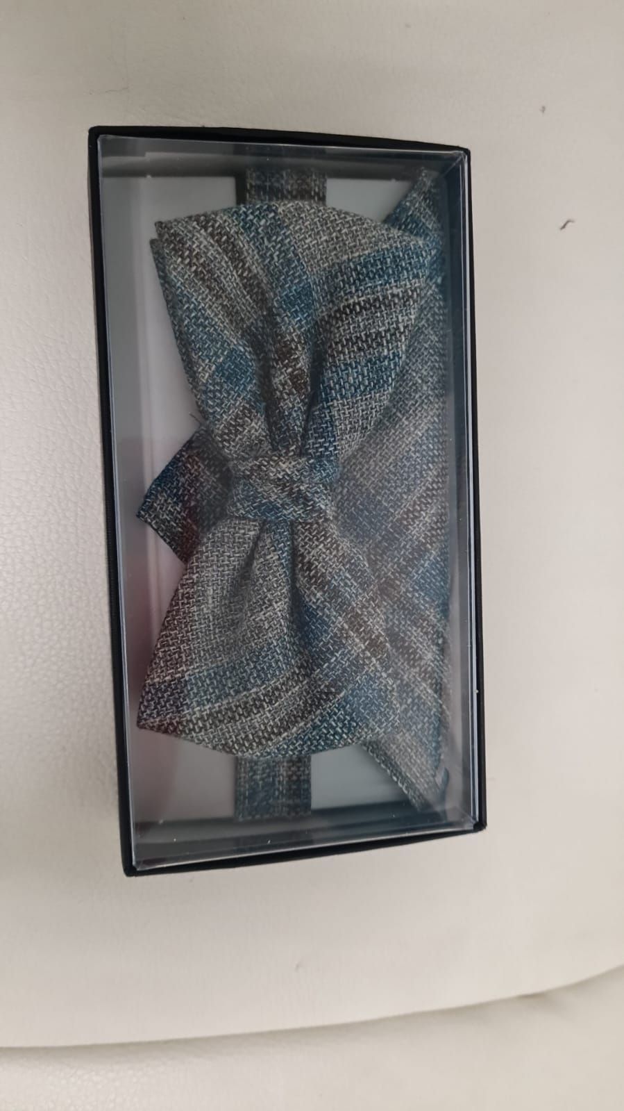 Eine Fliege und ein Einstecktuch in einer Schachtel auf einem Tisch.