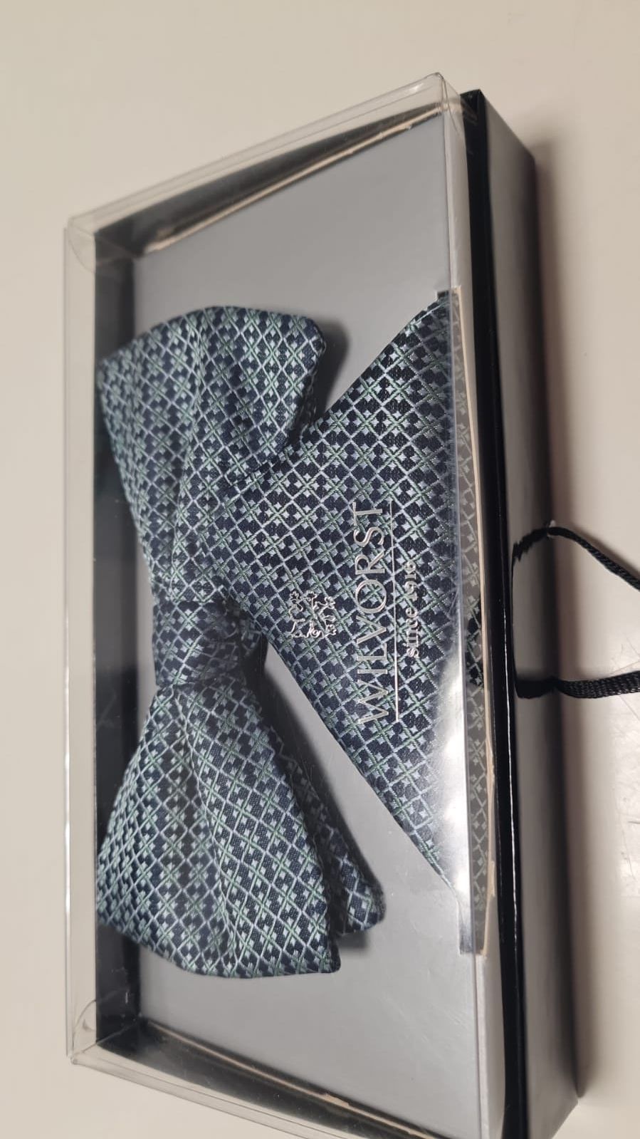 Eine Fliege und ein Einstecktuch befinden sich in einer Schachtel.