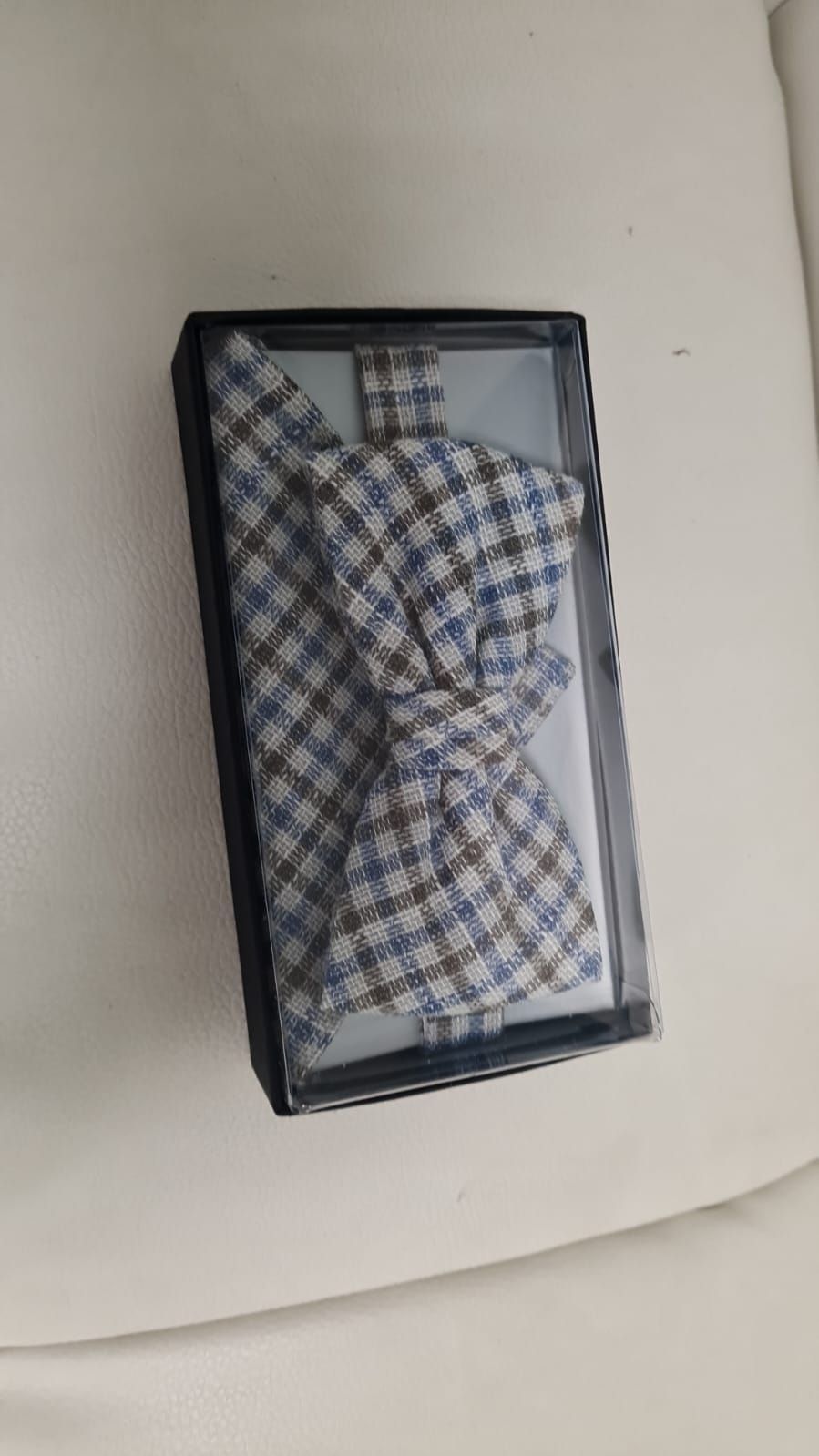 Eine Fliege und ein Einstecktuch befinden sich in einer Schachtel.