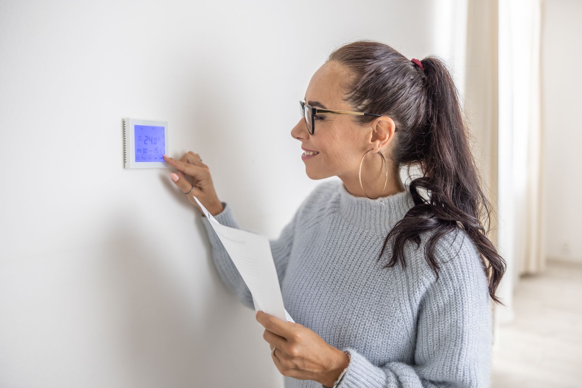 woman looking at her thermostat