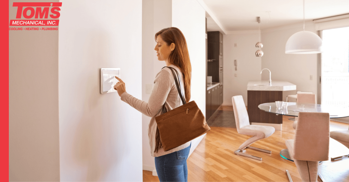 Woman pressing a smart home control panel on a wall in a modern apartment.