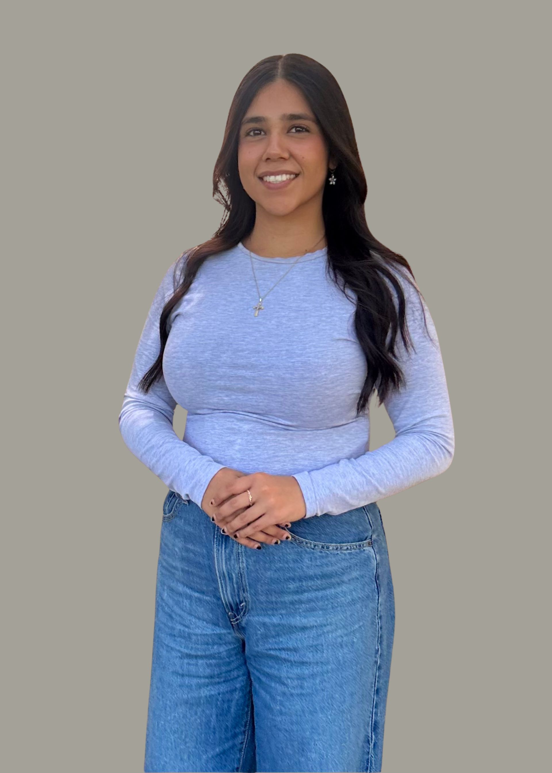 Woman in a white top and beige pants standing against a gray background, smiling at the camera | Westlake Independent Automotive