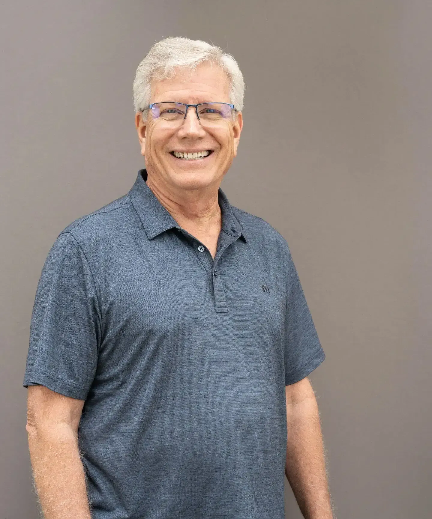 Smiling man in a blue polo shirt standing against a plain gray background | Westlake Independent Automotive