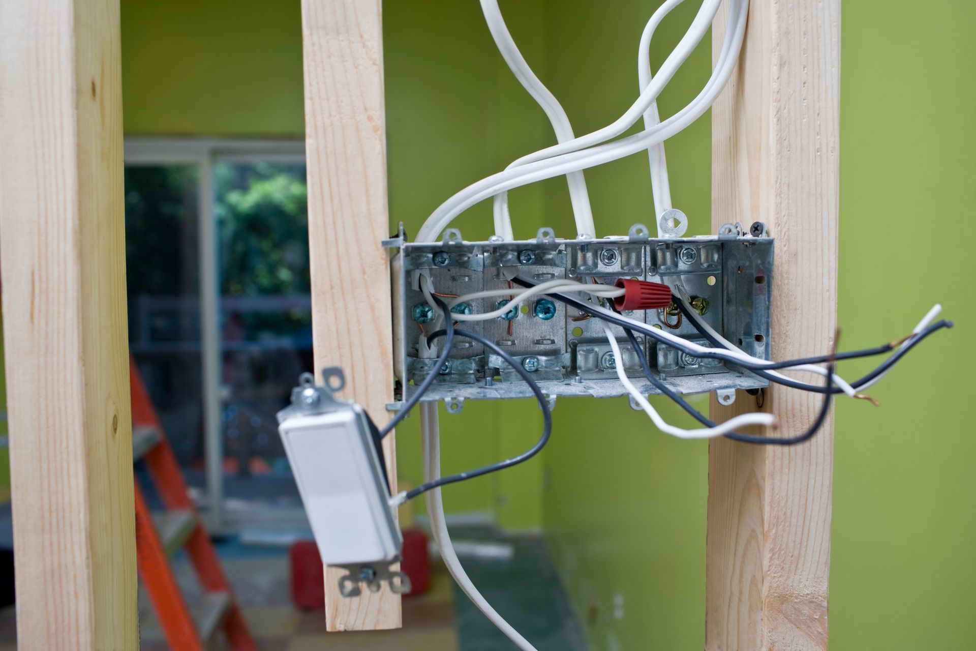 A box with wires coming out of it is attached to a wooden post.