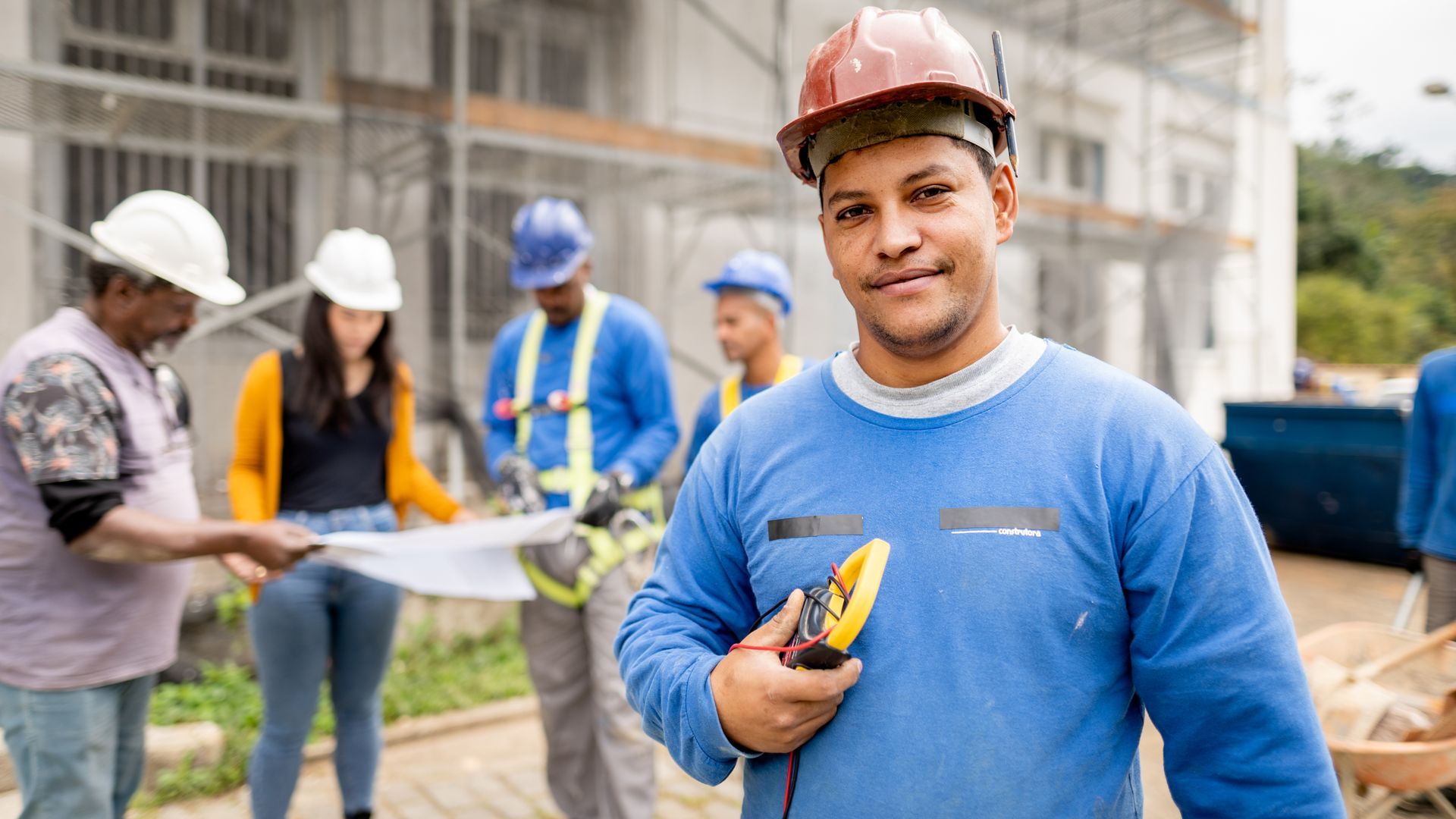 A construction worker is standing in front of a group of construction workers on a construction site.