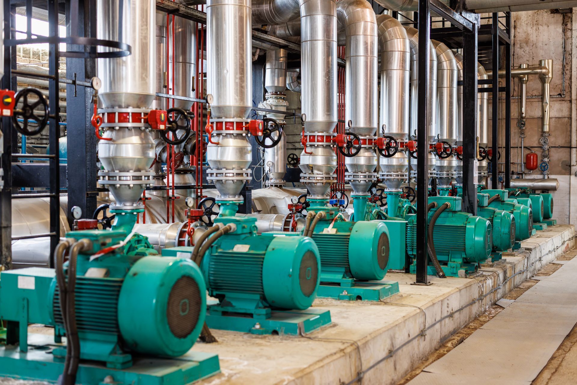 A row of green pumps are lined up in a factory.