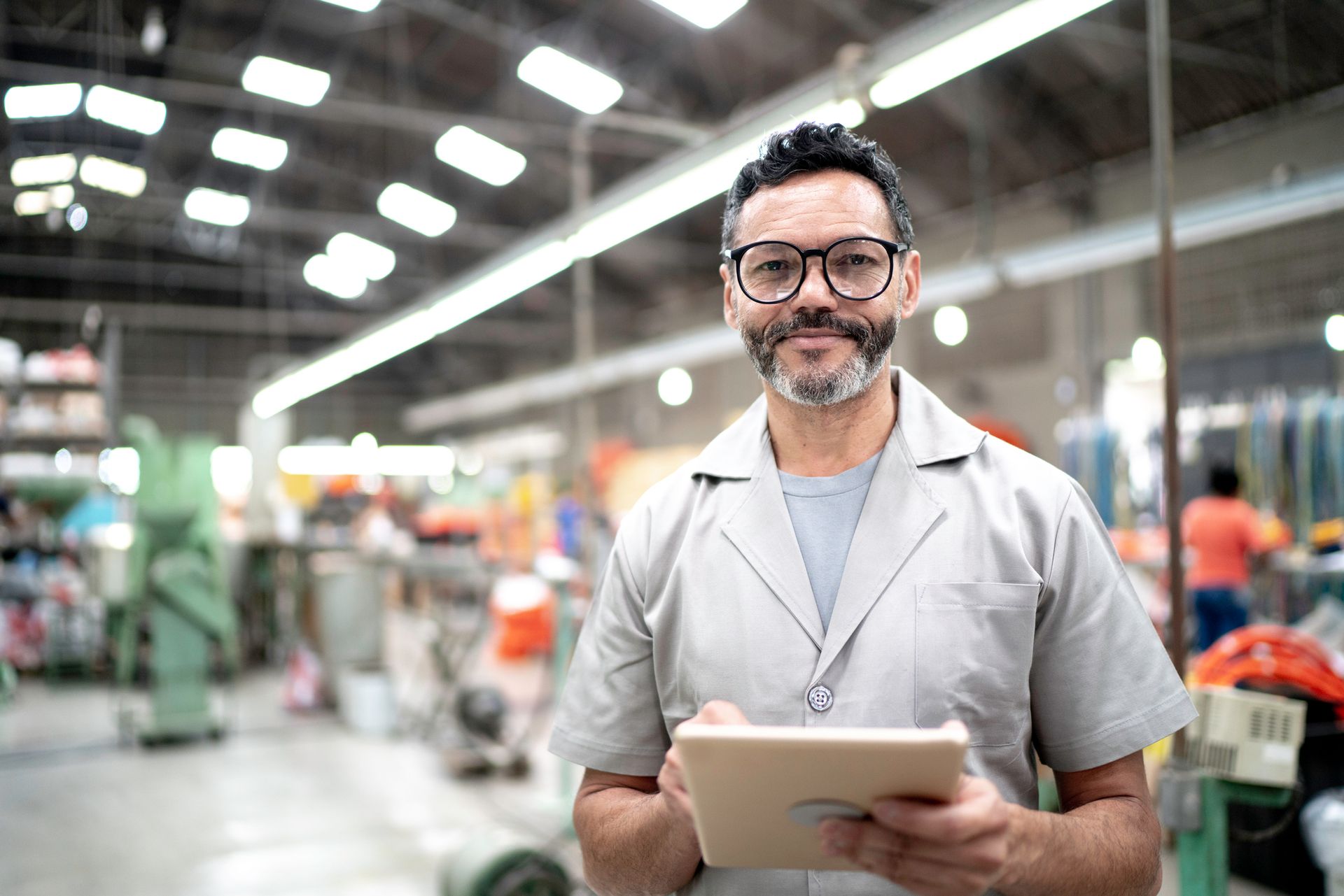 A man is holding a tablet in a factory.