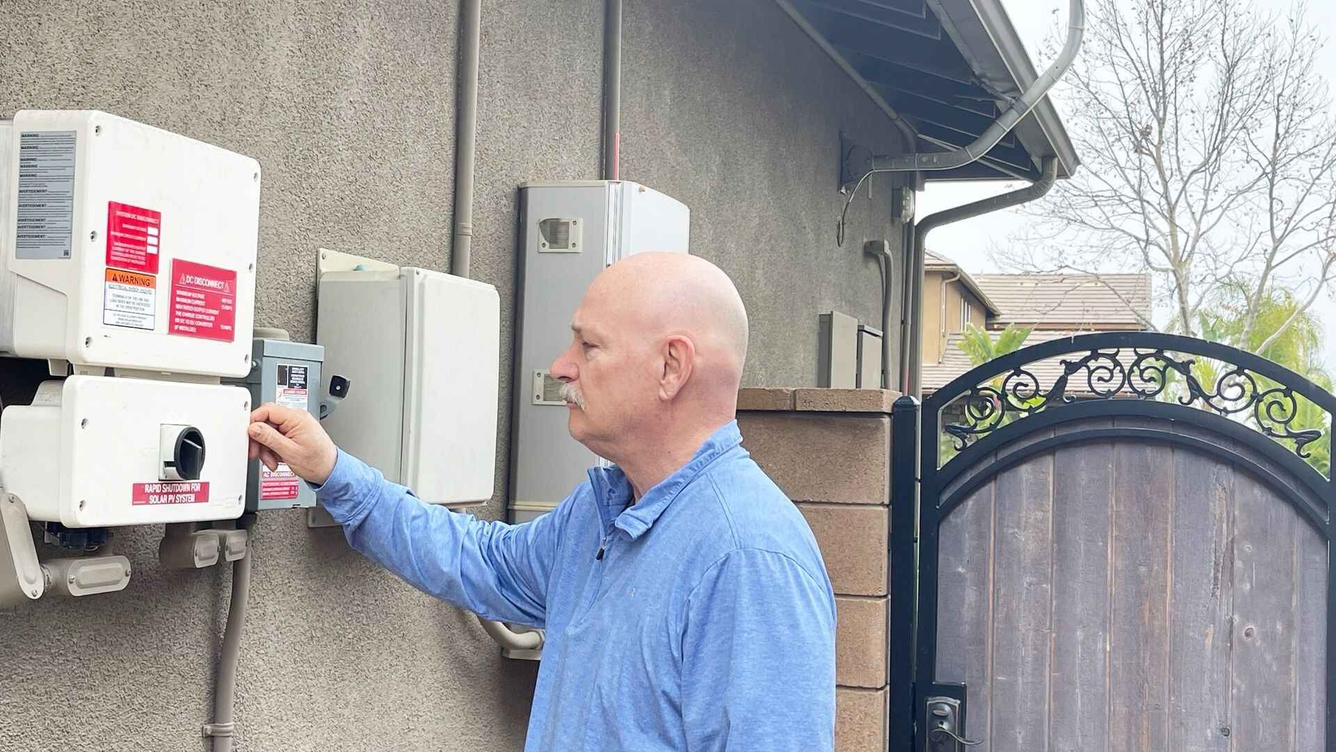 A man is working on a solar panel on the side of a building.