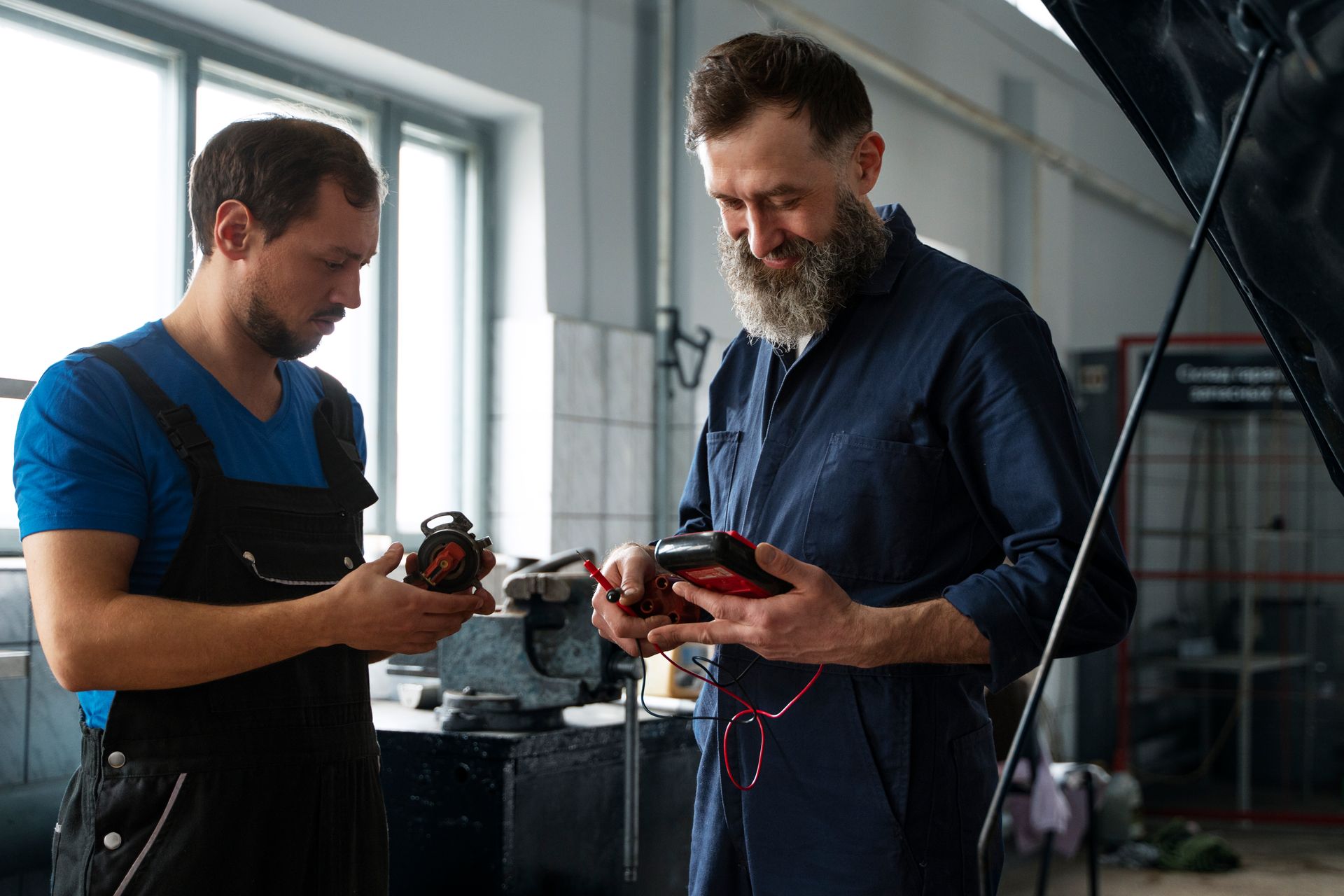 Two mechanics are working on a car in a garage.