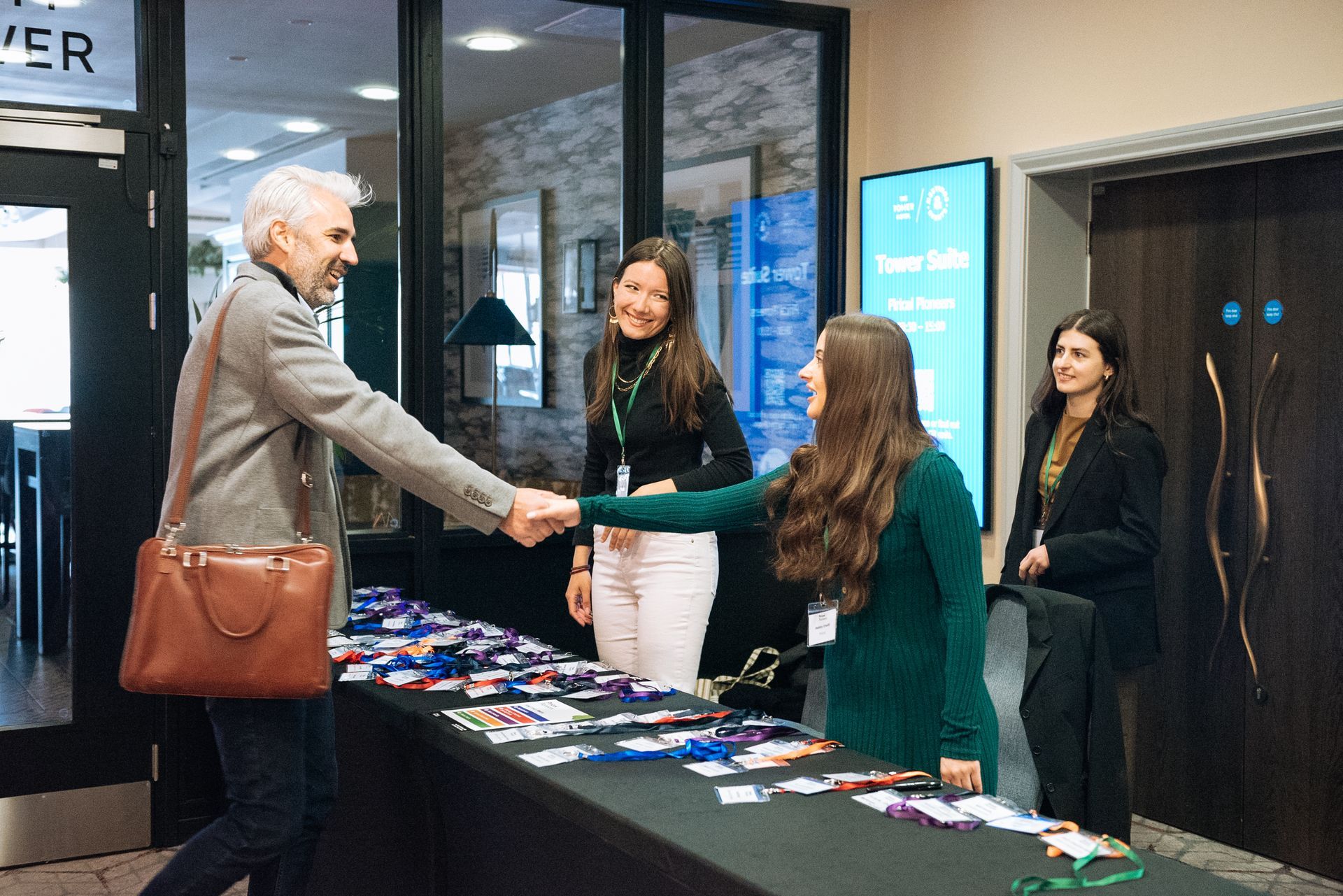 People at a registration table in a lobby, with brochures and name tags displayed.