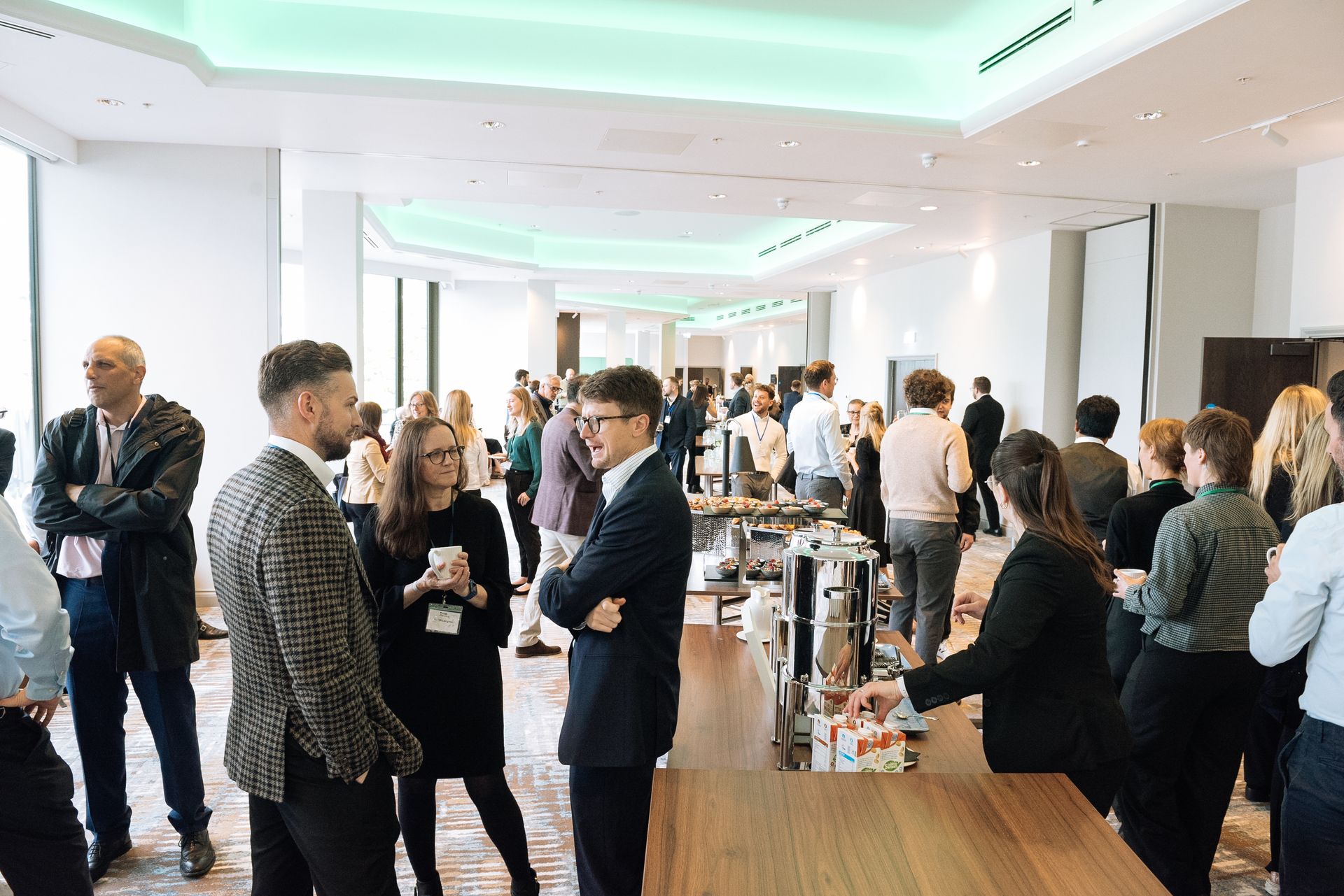 People mingling at a bright conference networking reception with drinks and conversation